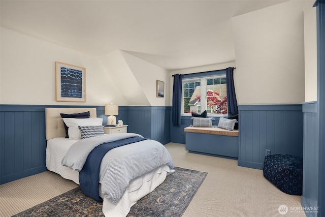 bedroom with carpet floors and a wainscoted wall