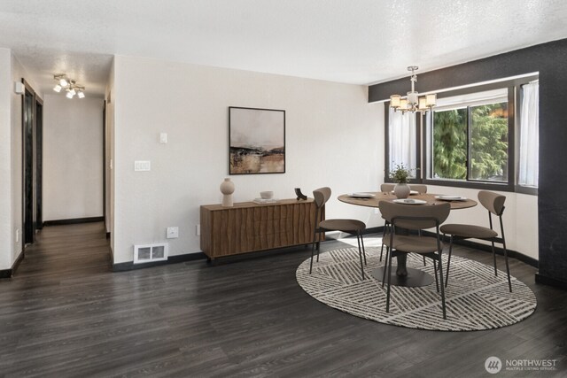 dining space with visible vents, baseboards, wood finished floors, and an inviting chandelier