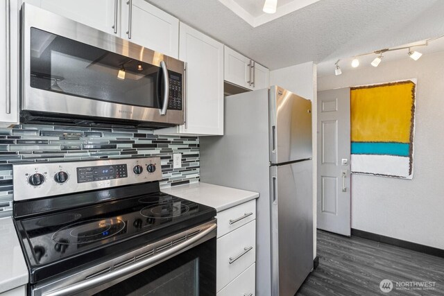 kitchen featuring tasteful backsplash, light countertops, baseboards, stainless steel appliances, and white cabinetry