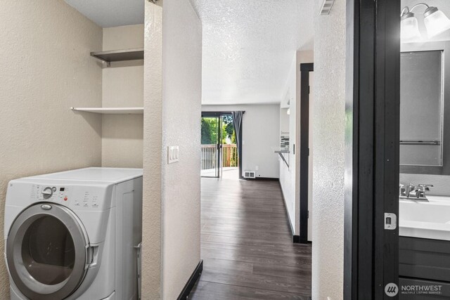 laundry area with washer / dryer, a textured wall, and dark wood-style floors