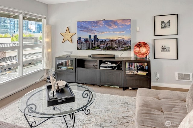 living area with baseboards, visible vents, and carpet