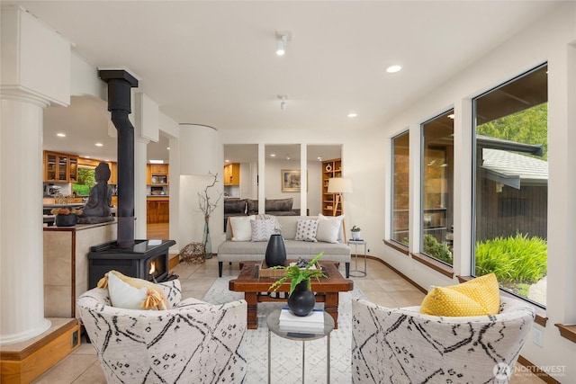 interior space with ornate columns, recessed lighting, light tile patterned floors, and a wood stove