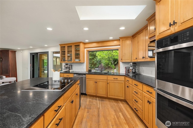 kitchen with light wood-type flooring, a sink, appliances with stainless steel finishes, and tasteful backsplash