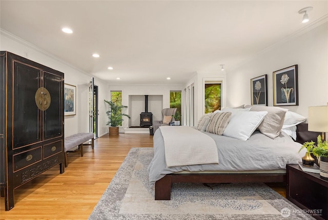 bedroom with recessed lighting, a wood stove, light wood finished floors, and multiple windows