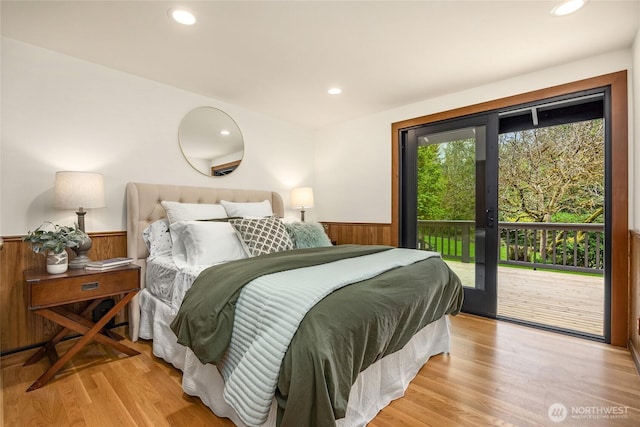 bedroom with access to outside, wainscoting, light wood-style floors, wood walls, and recessed lighting