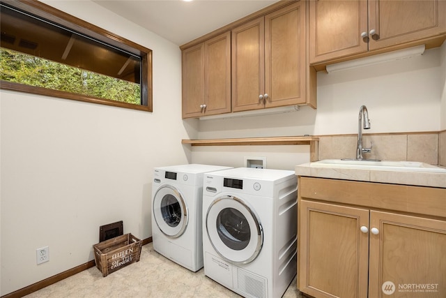 washroom featuring a sink, cabinet space, and washing machine and clothes dryer