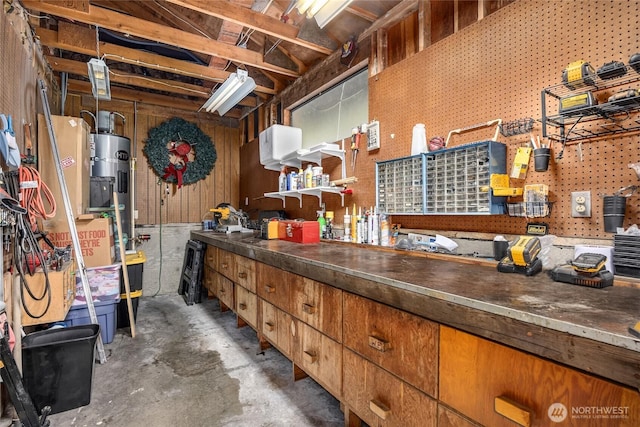 misc room featuring a workshop area, concrete floors, and electric water heater