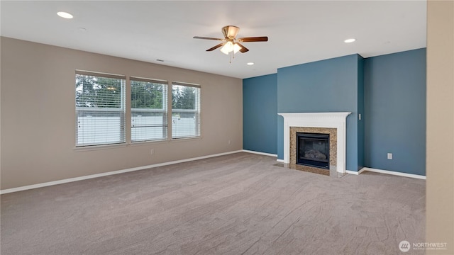unfurnished living room featuring a ceiling fan, a high end fireplace, baseboards, carpet, and recessed lighting