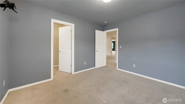 unfurnished bedroom featuring baseboards, carpet, and a walk in closet