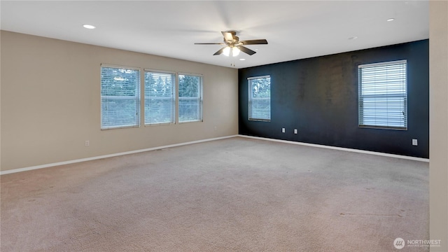 empty room featuring plenty of natural light, a ceiling fan, and baseboards