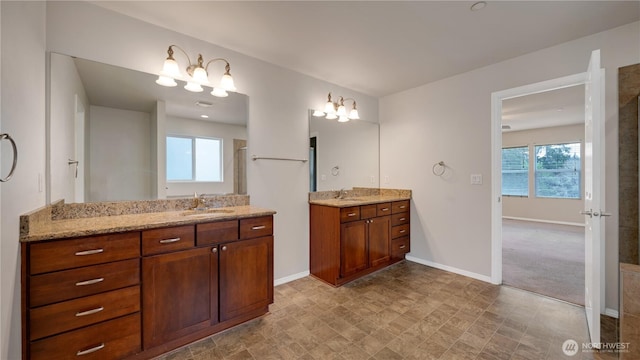 full bathroom with baseboards, two vanities, and a sink