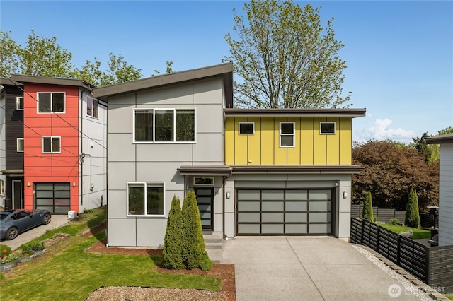 contemporary house featuring a garage, board and batten siding, fence, and driveway