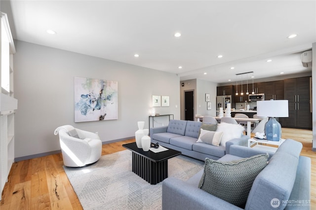 living room with baseboards, a wall mounted air conditioner, recessed lighting, and light wood-style flooring