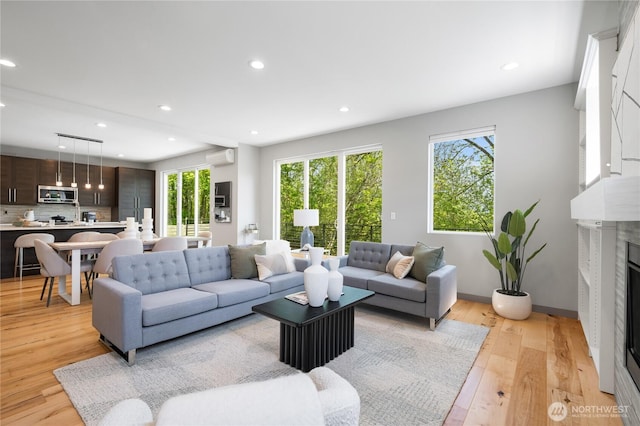 living area featuring plenty of natural light, recessed lighting, light wood finished floors, and a premium fireplace