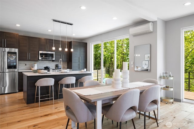 dining area featuring recessed lighting, a wall mounted air conditioner, and light wood-style flooring