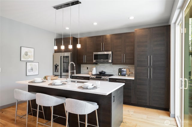 kitchen featuring stainless steel appliances, dark brown cabinetry, a breakfast bar, and a sink