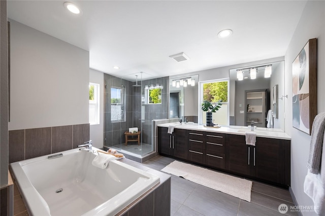 full bath featuring double vanity, tile patterned flooring, a stall shower, a sink, and tiled bath