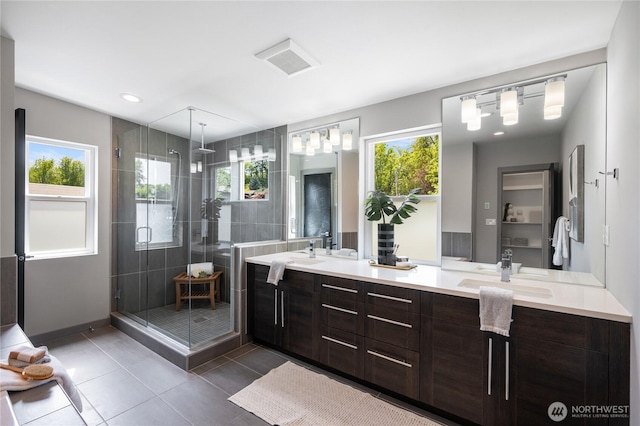 full bathroom featuring double vanity, plenty of natural light, and a shower stall