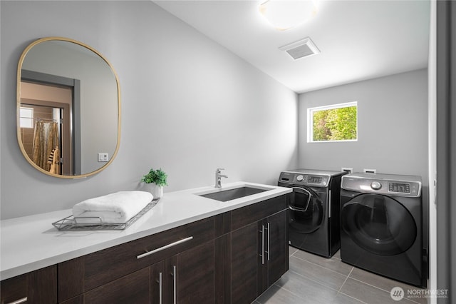 laundry area with cabinet space, washer and dryer, a sink, light tile patterned floors, and visible vents