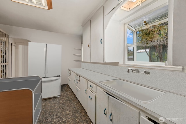 kitchen featuring a sink, open shelves, freestanding refrigerator, and light countertops
