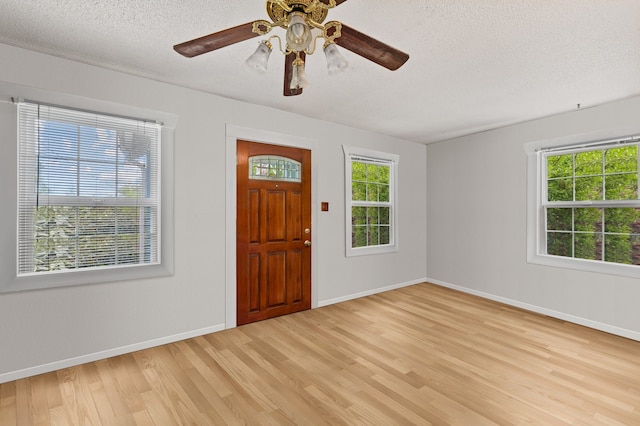 entrance foyer with plenty of natural light, a textured ceiling, and light wood finished floors