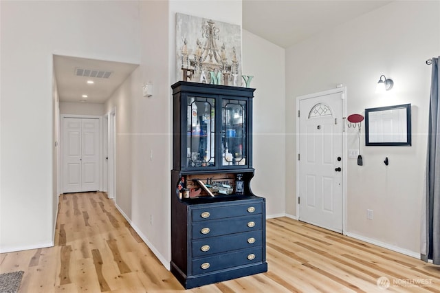 entryway with baseboards, visible vents, and light wood finished floors