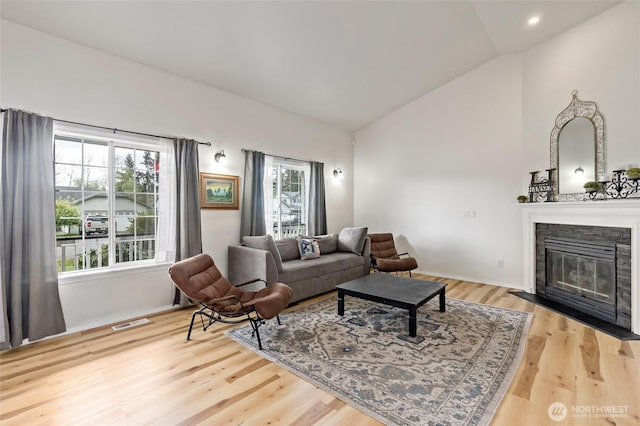 living area featuring a fireplace, light wood-style floors, recessed lighting, lofted ceiling, and visible vents