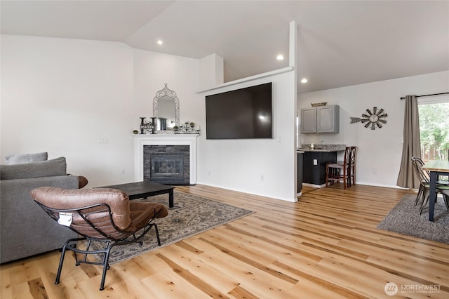 living area featuring lofted ceiling, recessed lighting, light wood-style flooring, and a tile fireplace