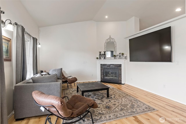 living room featuring a fireplace with flush hearth, recessed lighting, wood finished floors, and lofted ceiling