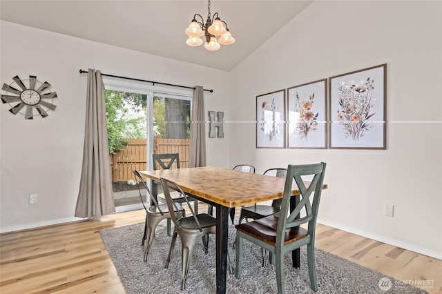 dining room featuring baseboards, an inviting chandelier, vaulted ceiling, and light wood-type flooring