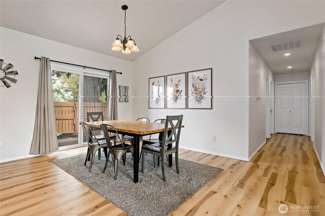 dining area featuring visible vents, a chandelier, lofted ceiling, and light wood finished floors