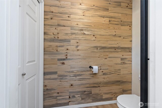 bathroom with toilet and wood walls