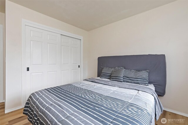bedroom with baseboards, a closet, and wood finished floors