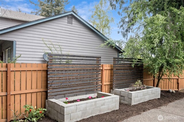view of side of property with a fenced backyard and a garden