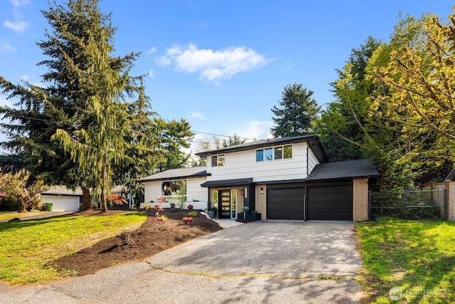 split level home with an attached garage, fence, a front yard, and aphalt driveway
