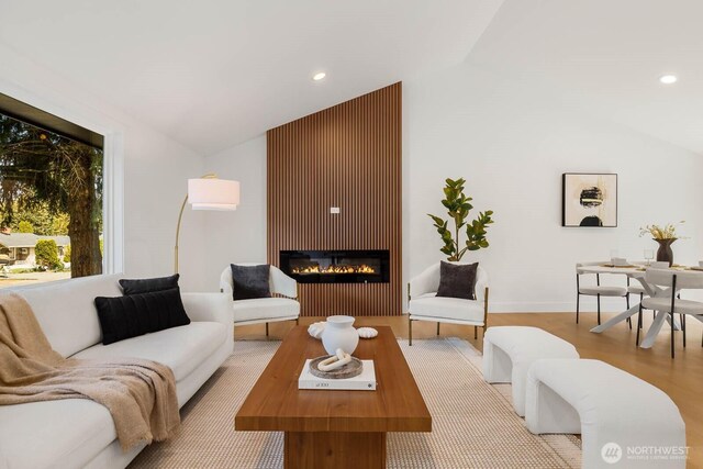 living area featuring a glass covered fireplace, recessed lighting, and lofted ceiling