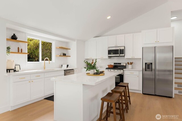 kitchen featuring a center island, open shelves, light wood-style flooring, and stainless steel appliances