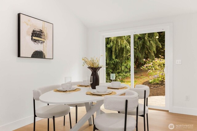 dining area featuring baseboards, vaulted ceiling, and light wood-style flooring