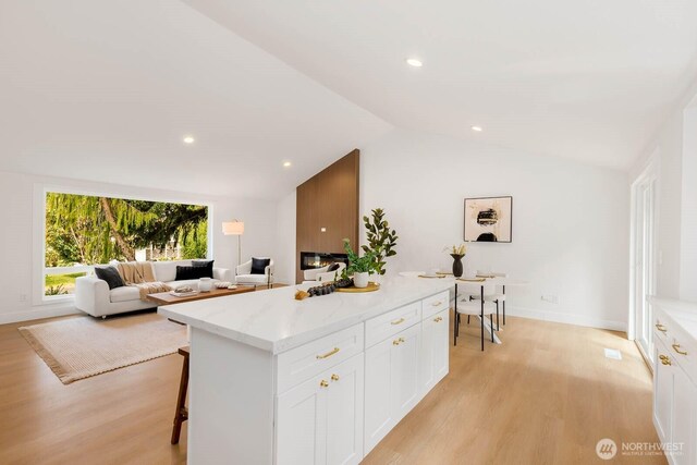 kitchen featuring white cabinets, light wood-style flooring, and lofted ceiling