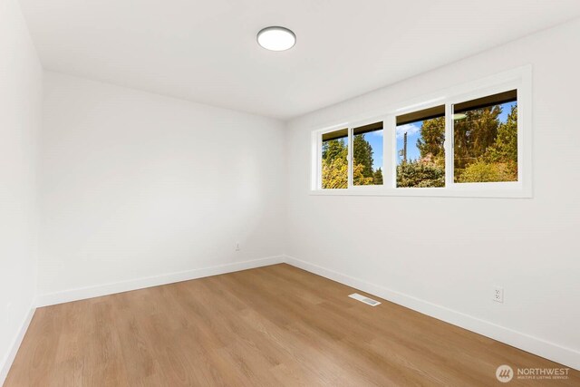 empty room with baseboards, light wood-type flooring, and visible vents