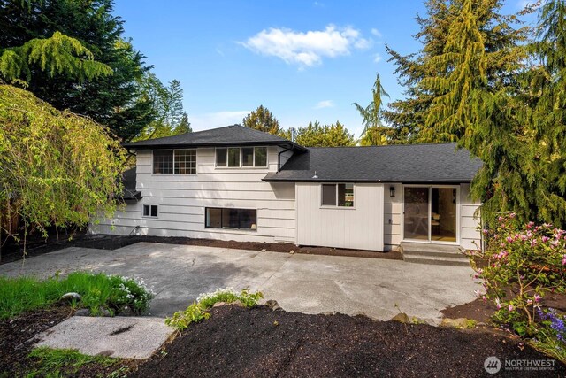 view of front of house with a shingled roof and a patio area