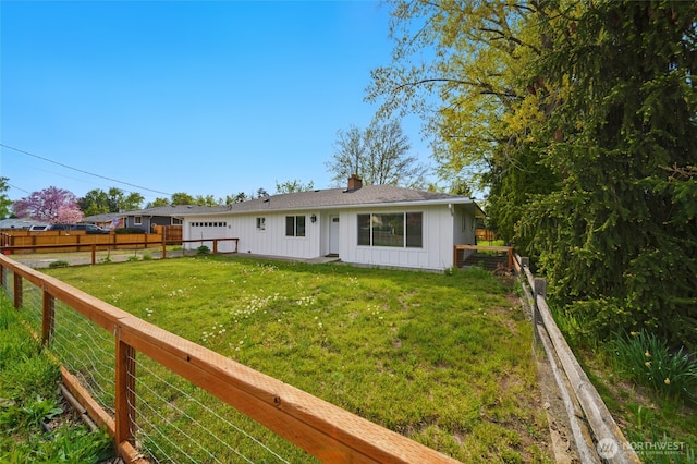 back of property with a lawn, a fenced backyard, board and batten siding, and a chimney