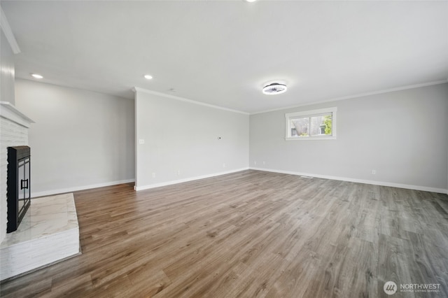 unfurnished living room with ornamental molding, wood finished floors, and baseboards