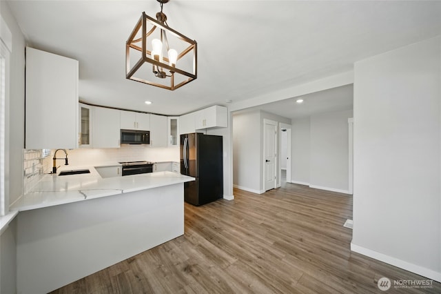 kitchen with black appliances, light countertops, decorative backsplash, and baseboards