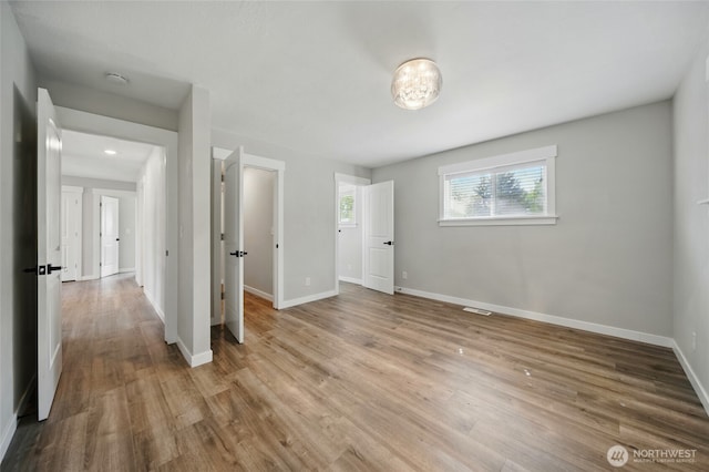 unfurnished bedroom with baseboards, visible vents, and wood finished floors
