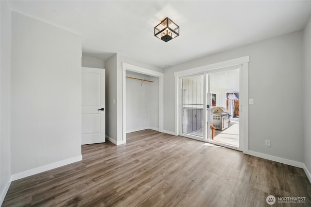 unfurnished bedroom with a closet, wood finished floors, and baseboards