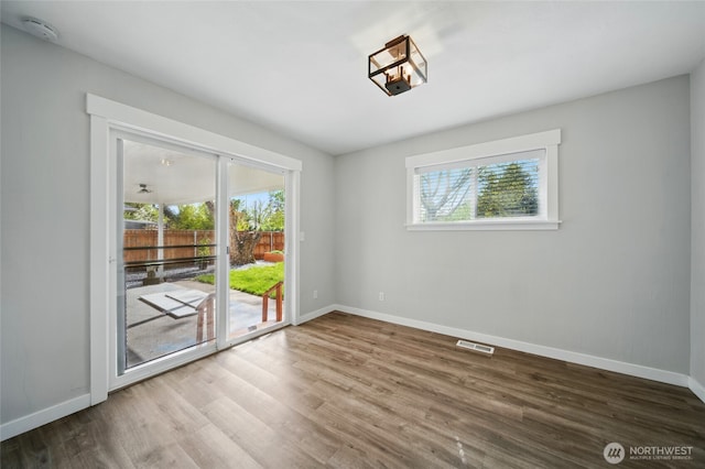 unfurnished room featuring visible vents, wood finished floors, and baseboards