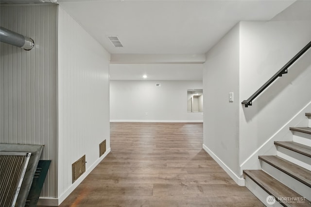 interior space featuring baseboards, visible vents, wood finished floors, and stairs