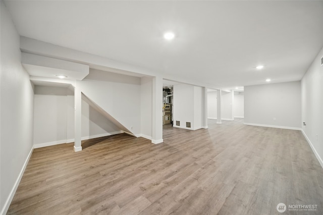 finished below grade area with light wood finished floors, recessed lighting, visible vents, and baseboards