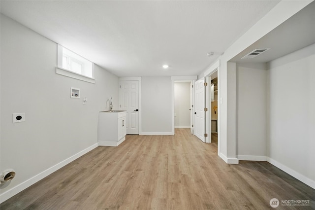basement with a sink, visible vents, light wood finished floors, and baseboards